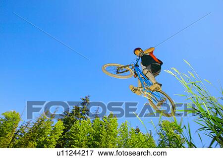 Mountain biker in air against blue sky View Large Photo Image Stock Photo - Mountain biker in air against blue sky. Fotosearch