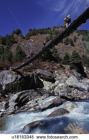 Stock Photography - People crossing a rope bridge above a river. Fotosearch
