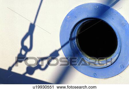 Stock Image - Porthole and shadow of stays rigging on white boat. Fotosearch