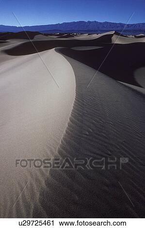 Stock Image - Ripples in desert sand with mountain in background. Fotosearch