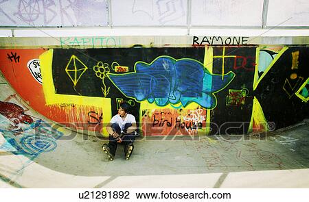 Stock Image - Skater sitting in park. Fotosearch