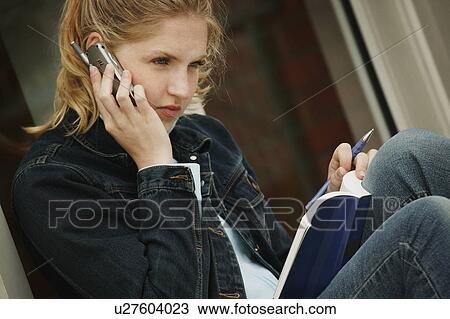 Stock Image - Student with book and cell phone. Fotosearch