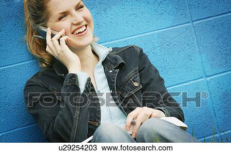 Stock Image - Student with textbook and cell phone. Fotosearch
