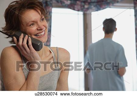 Wife chats on phone while husband waits View Large Photo Image Picture - Wife chats on phone while husband waits. Fotosearch