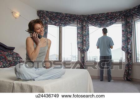 Wife chats on phone while husband waits View Large Photo Image Stock Photo - Wife chats on phone while husband waits. Fotosearch