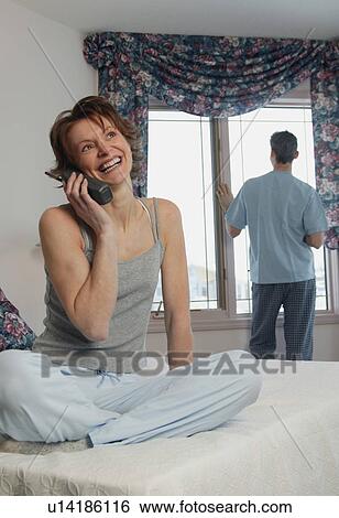 Wife chats on phone while husband waits View Large Photo Image Stock Photograph - Wife chats on phone while husband waits. Fotosearch