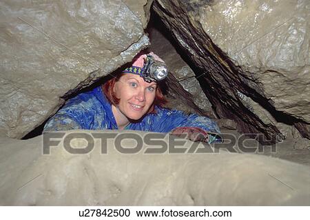 Stock Image - Woman exploring underground cave. Fotosearch