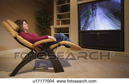 Picture - Woman relaxes in front of television. Fotosearch