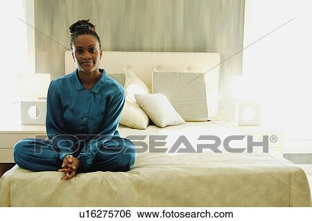Woman sits cross-legged on a bed View Large Photo Image Stock Photograph - Woman sits cross-legged on a bed. Fotosearch