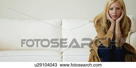 Woman sits on sofa View Large Photo Image Stock Image - Woman sits on sofa. Fotosearch
