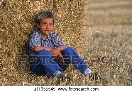 Stock Photography - Young boy relaxing in the hayfield. Fotosearch