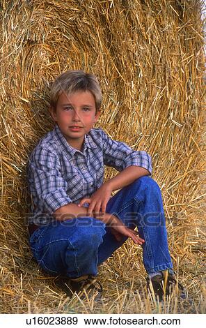 Stock Photo - Young boy sitting on hay bale. Fotosearch