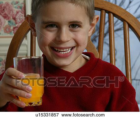 Stock Photo - Young boy smiling and holding orange juice. Fotosearch