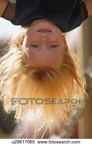 Young girl hanging upside down in the playground on an autumn day View Large Photo Image Stock Photography - Young girl hanging upside down in the playground on an autumn day. Fotosearch