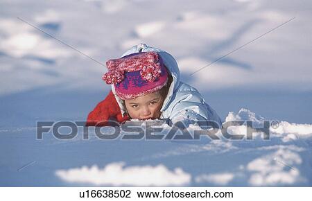 Stock Image - Young girl playing in the snow on a winter afternoon. Fotosearch