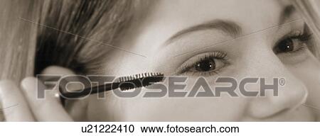 Young woman putting on mascara View Large Photo Image Stock Image - Young woman putting on mascara. Fotosearch
