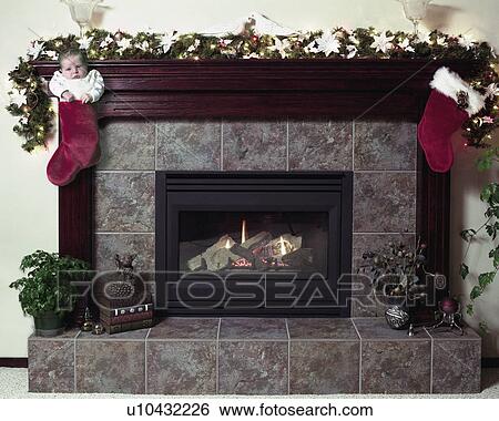 Stock Photograph - Baby in Christmas stocking by fireplace. Fotosearch