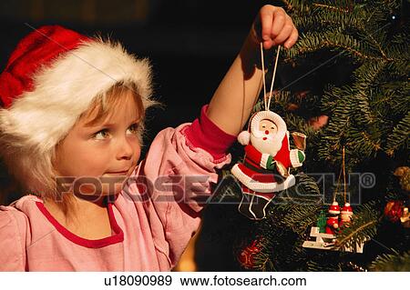 Stock Photo - Girl Hanging Ornament on Christmas Tree. Fotosearch