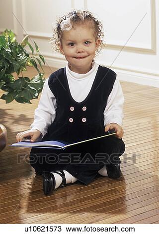 Stock Image - Girl reading book on floor. Fotosearch