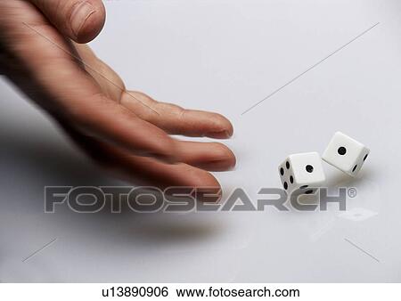 Stock Photograph - Hand rolling dice on white surface. Fotosearch