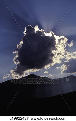 Sun behind a cloud above mountain range View Large Photo Image Stock Photo - Sun behind a cloud above mountain range. Fotosearch