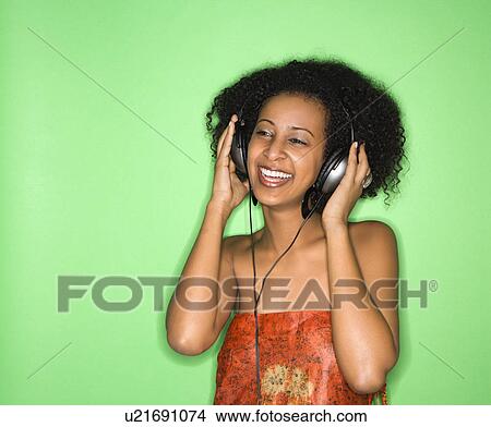 Picture - African-American woman listening to music through headphones.. Fotosearch