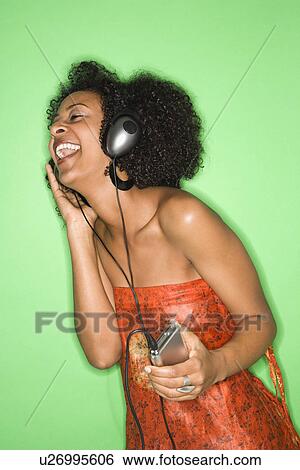 African-American woman listening to music through headphones. View Large Photo Image Stock Photograph - African-American woman listening to music through headphones.. Fotosearch