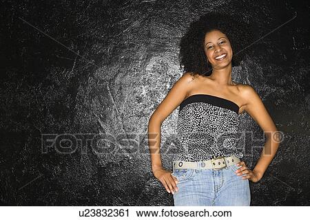 Stock Image - African-American woman standing with hands on hips.. Fotosearch
