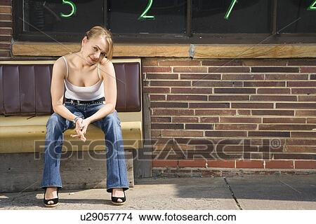 Attractive young Caucasian woman sitting on bench outside. View Large Photo Image Picture - Attractive young Caucasian woman sitting on bench outside.. Fotosearch