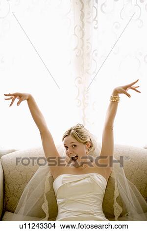 Caucasian bride on love seat with arms raised and joyful expression. View Large Photo Image Picture - Caucasian bride on love seat with arms raised and joyful expression.. Fotosearch