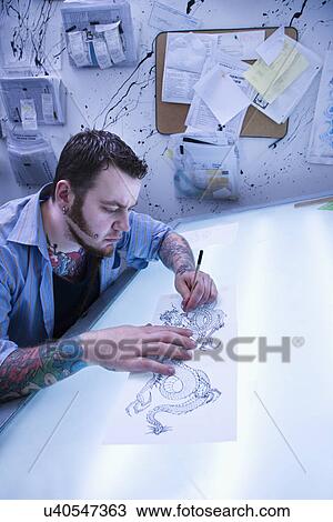 Caucasian male tattoo artist drawing tattoo on light table. View Large Photo Image Stock Image - Caucasian male tattoo artist drawing tattoo on light table.. Fotosearch