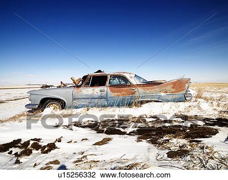Stock Image - Classic rusted car in snowy junkyard.. Fotosearch