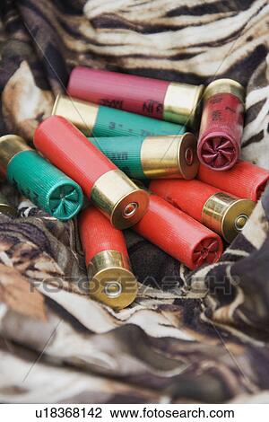 Stock Image - Still life shot of shotgun shells against camouflage clothing.. Fotosearch