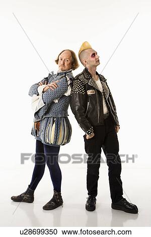 Stock Image - William Shakespeare in period clothing and gothic punk young man standing back to back with arms crossed.. Fotosearch
