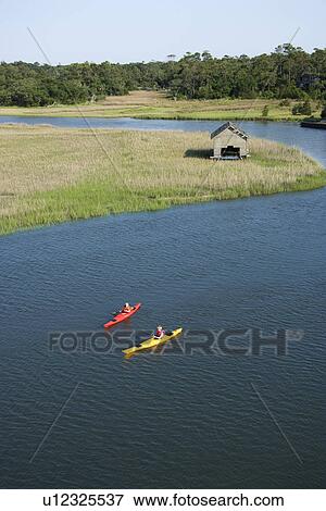 Stock Photo - Aerial of two teenage boys kayaking through marshland on Bald Head Island, North Carolina.. Fotosearch