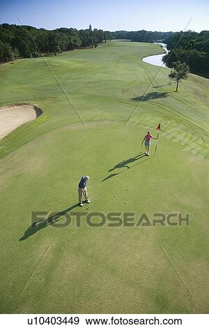 Stock Photo - Aerial view of mid adult Caucasian man and woman playing golf at Bald Head Island, North Carolina.. Fotosearch