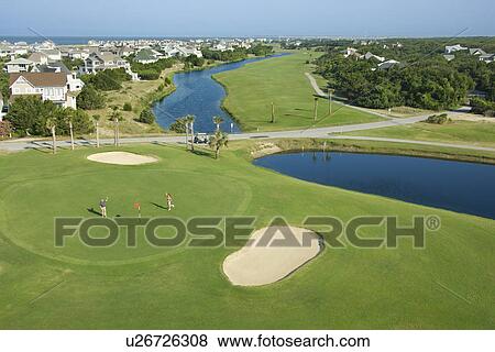 Stock Photo - Aerial view of two people palying golf near residential community at Bald Head Island, North Carolina.. Fotosearch