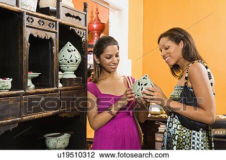 Stock Image - African American and Indian women shopping together for home decor.. Fotosearch
