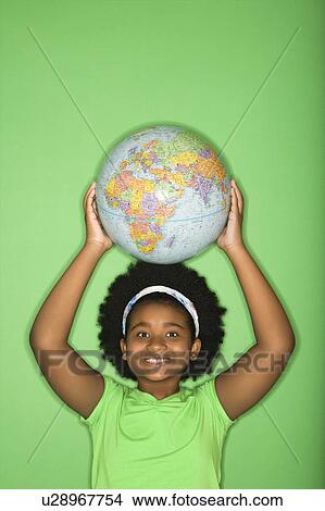Picture - African American girl holding globe on top of head and smiling at viewer.. Fotosearch