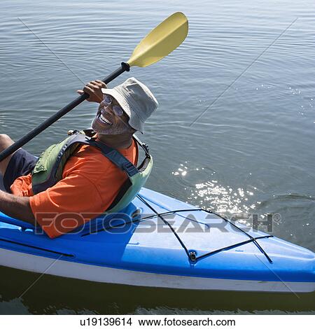 Picture - African American middle-aged man smiling at viewer in kayak.. Fotosearch