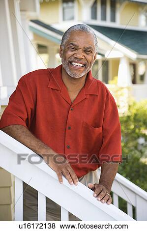 Stock Photo - African American middle aged man smiling at viewer and leaning on stairway railing.. Fotosearch
