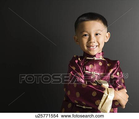 Picture - Asian boy in traditional attire standing against black background.. Fotosearch