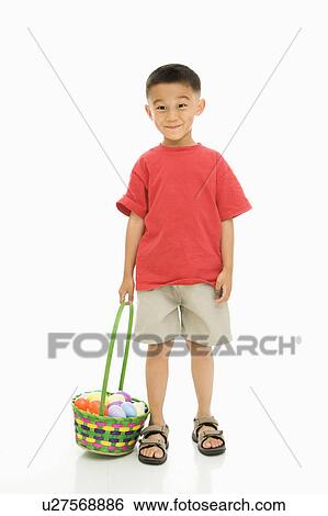 Stock Photograph - Asian boy standing against white background holding Easter basket.. Fotosearch