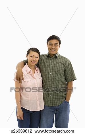 Stock Image - Asian man and woman standing with arms around eachother.. Fotosearch