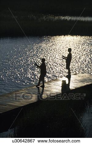 Stock Photo - Birds eye view of two teenage boys fishing from dock at Bald Head Island, North Carolina.. Fotosearch