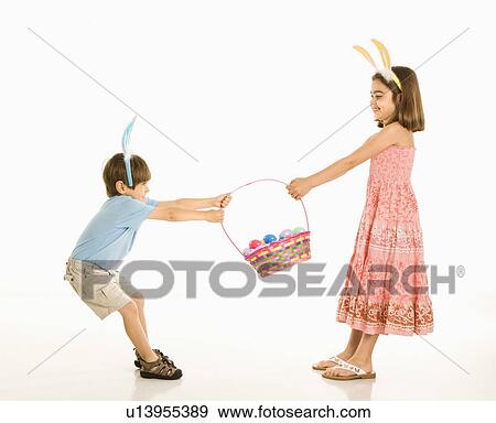 Stock Photo - Boy and girl wearing bunny ears fighting over Easter basket.. Fotosearch