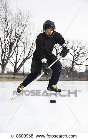 Boy in ice hockey uniform skating on ice rink moving puck. View Large Photo Image Stock Photo - Boy in ice hockey uniform skating on ice rink moving puck.. Fotosearch