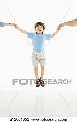 Boy jumping into air holding hands with parents against white background. View Large Photo Image Stock Image - Boy jumping into air holding hands with parents against white background.. Fotosearch