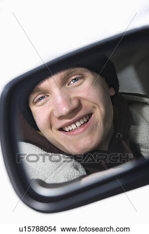 Caucasian male teenager looking at himself in side view mirror of car. View Large Photo Image Picture - Caucasian male teenager looking at himself in side view mirror of car.. Fotosearch