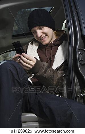 Stock Photography - Caucasian male teenager text messaging with cellphone.. Fotosearch